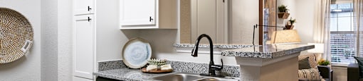 an open kitchen and living room with white cabinets and a counter top