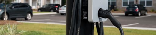 a close up of a charging station on a sidewalk with an apartment building in the background