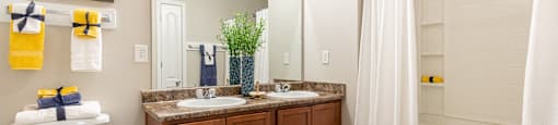 A bathroom with a white toilet, a sink with a brown cabinet, and a shower with a white curtain.