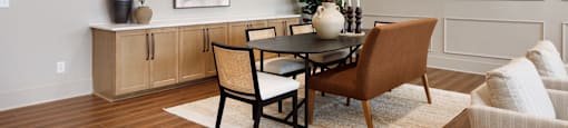 A dining room with a table set for two and a vase of flowers on the table.