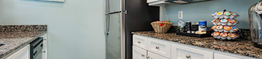 A kitchen with a black refrigerator and white cabinets.