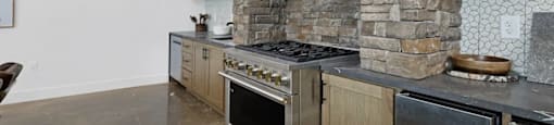 A modern clubhouse kitchen with a stone fireplace and stainless steel appliances at Terraces at High Mountain apartments in Huntsville, AL.