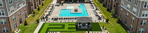 an aerial view of a pool in front of an apartment building