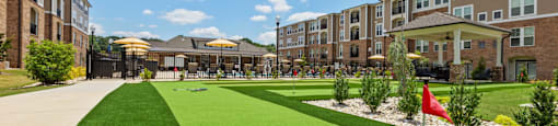 a green lawn in front of an apartment complex with a flag in the grass