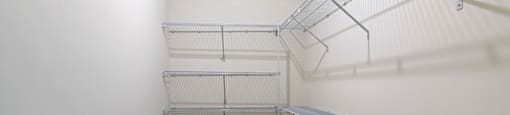 a walk in closet with white walls and metal shelves