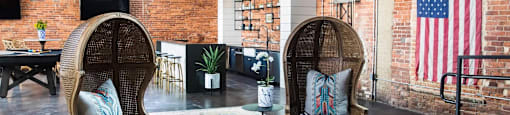 Two chairs with blue cushions are in front of a brick wall.