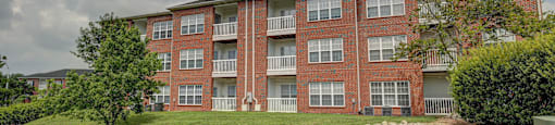 A red brick apartment building with a green lawn in front.