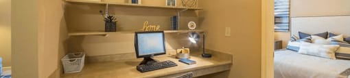 a bedroom with a desk with a computer and a bed