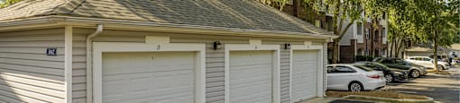 a small garage with white doors on the side of a street