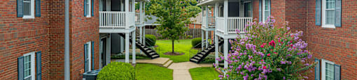 an image of an apartment complex with a walkway and grass