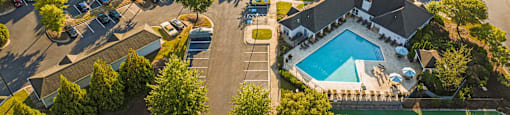an aerial view of a neighborhood with a swimming pool and cars in a parking lot