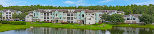 a fountain in the middle of a lake with houses in the background