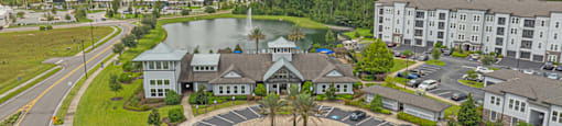 an aerial view of an apartment complex with a pond and parking lot