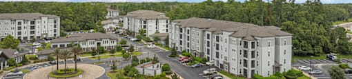an aerial view of an apartment complex with parking lot and trees
