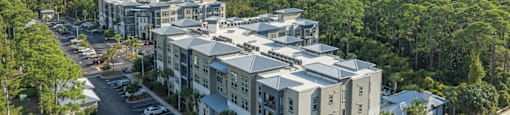 an aerial view of an apartment complex with trees and a parking lot
