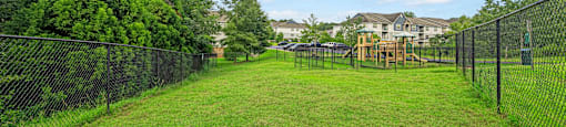 a fenced in yard with a playground and trees