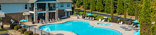 an aerial view of a swimming pool and resort building with umbrellas
