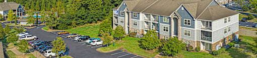 an aerial view of an apartment complex with parking lot and trees