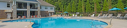 a swimming pool with chairs around it in front of a house