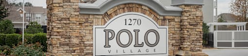 A stone wall with a sign that says Polo Village.