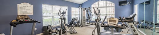 A gym with treadmills, exercise bikes, and a fan.