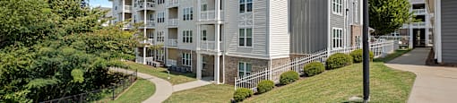 an apartment building on a sidewalk next to a grass field