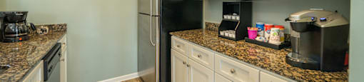 A kitchen with a refrigerator, microwave, and coffee maker.