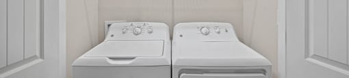 a white laundry room with two washes and a dryer