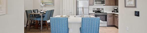 an open kitchen and dining area with blue chairs and a white counter top