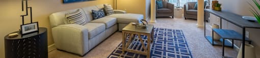 A living room with a couch, a painting, and a rug.