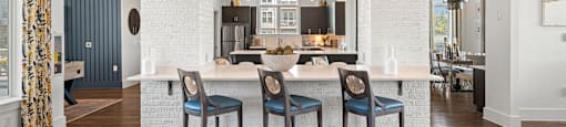 a large kitchen with a white island and blue chairs