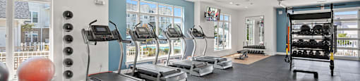 a gym with cardio machines and weights on the floor and windows