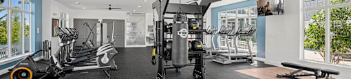 a gym with treadmills and other exercise equipment in a room with windows