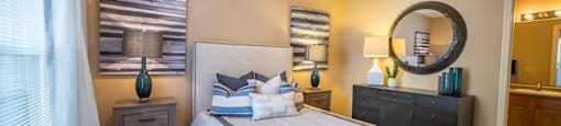 A bedroom with a large bed, a dresser, and a mirror.