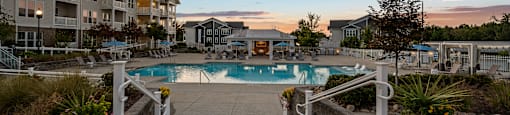 a swimming pool at sunset with apartments in the background
