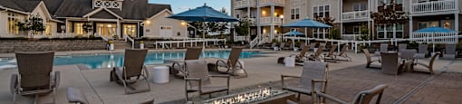 a swimming pool with chairs and umbrellas at dusk