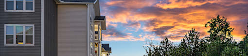 a winding sidewalk between two buildings with a sunset in the background