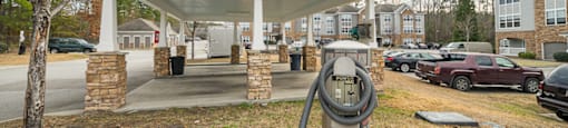 A parking lot with a charging station and a building in the background.
