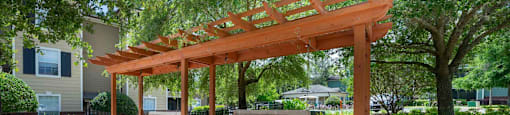 a wooden structure on a brick patio with trees