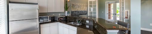 a kitchen with white cabinets and granite counter tops and a stainless steel refrigerator