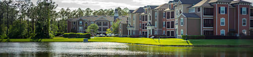a row of houses on a field with a reflection of a city in the water