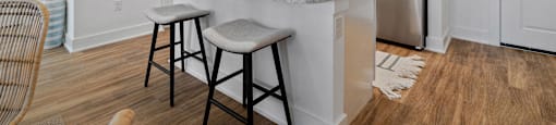 A kitchen with a white island and bar stools.