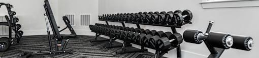 A gym with a variety of equipment including a bench, weights, and a fan.