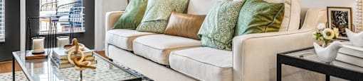 A living room with a white couch and a glass coffee table.