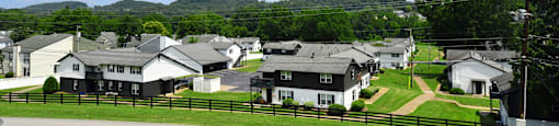 an aerial view of a neighborhood of white and black houses on a grassy field with a