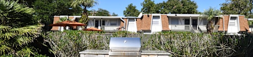 a picnic table and a grill in a yard in front of a house