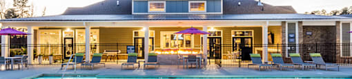 a swimming pool with chairs and a building in the background