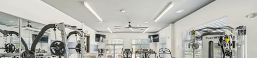 a gym with weights and cardio machines and a ceiling fan