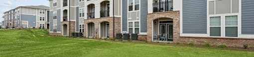 an exterior view of an apartment building with green grass