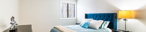 A bedroom with a bed, nightstand, and a lamp.